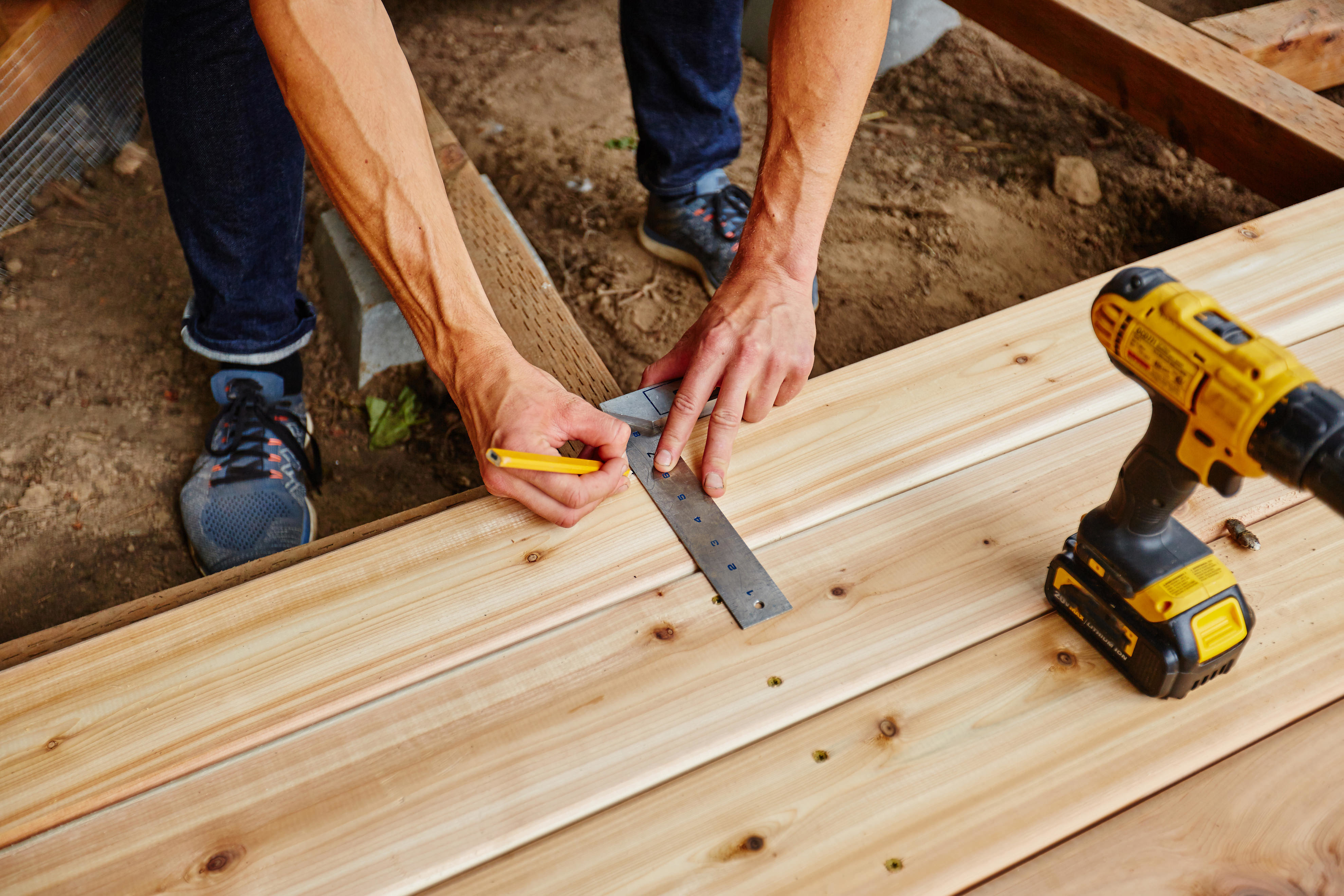 man drilling and measuring wood for deck